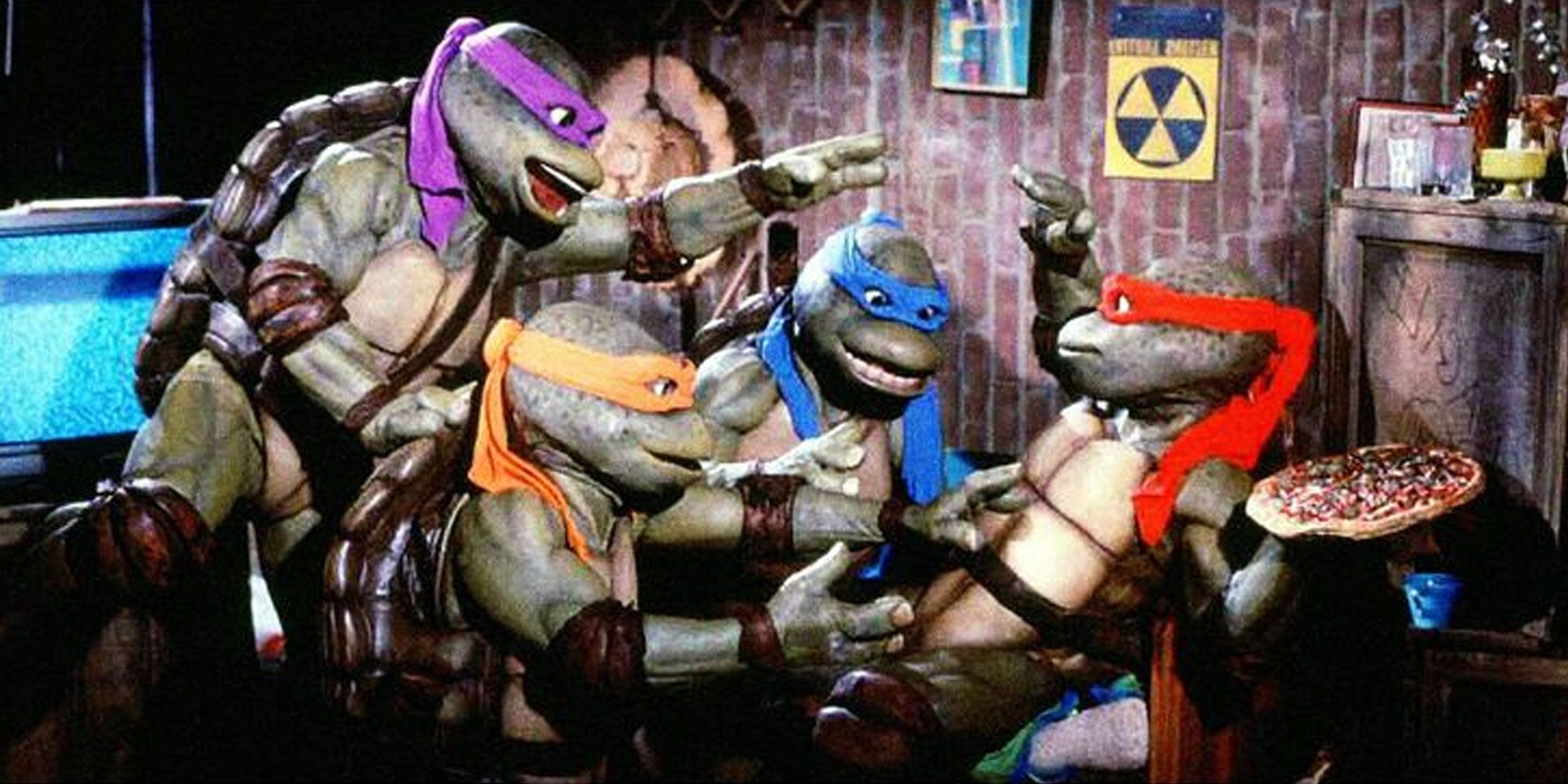 Raphael holds a pizza just out of reach from his brothers in the 90s Teenage Mutant Ninja Tutles live action movie