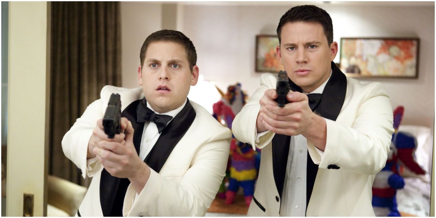 Schmidt and Jenko wearing tuxedos and pointing their guns at someone