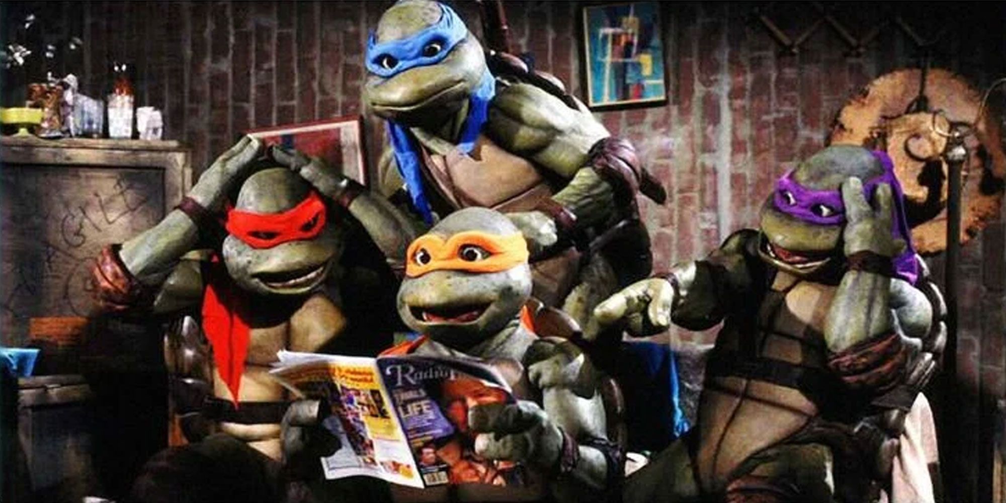 The 90s live action Teenage Mutant Ninja Turtles sit together and look at a magazine