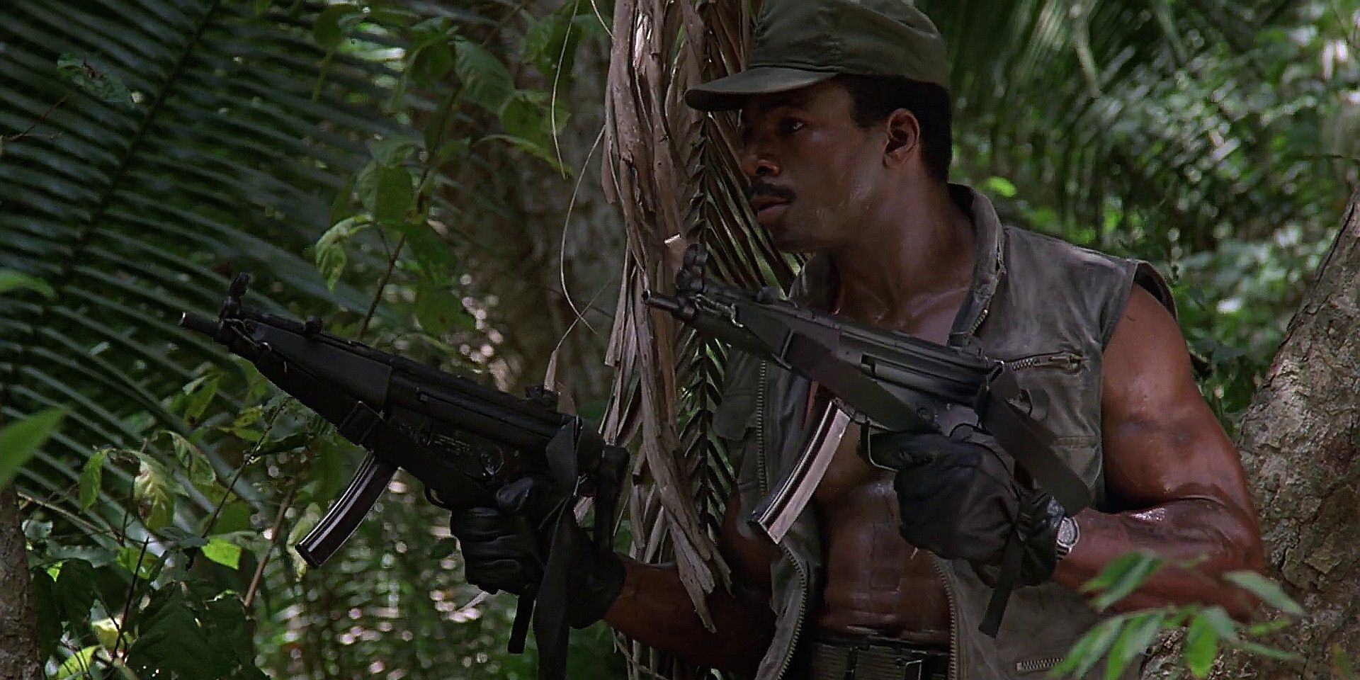 Carl Weathers holding two guns in the jungle in Predator