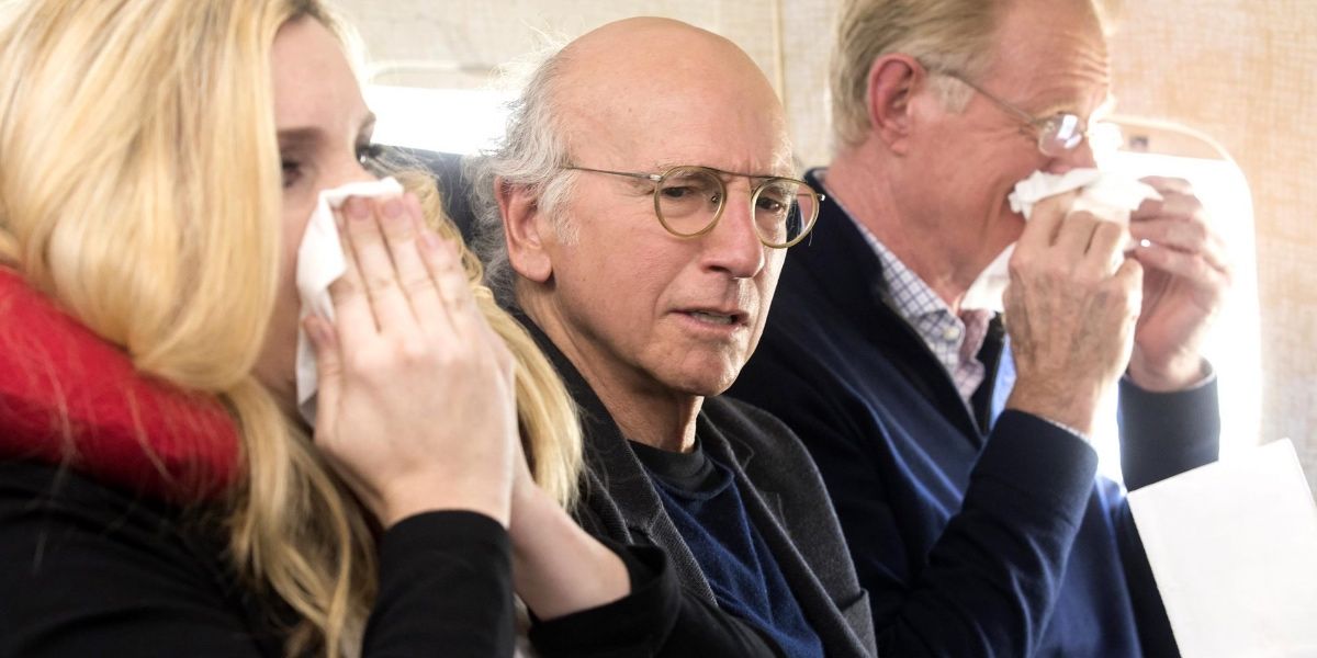 Larry David sitting in between sick people in Curb Your Enthusiasm