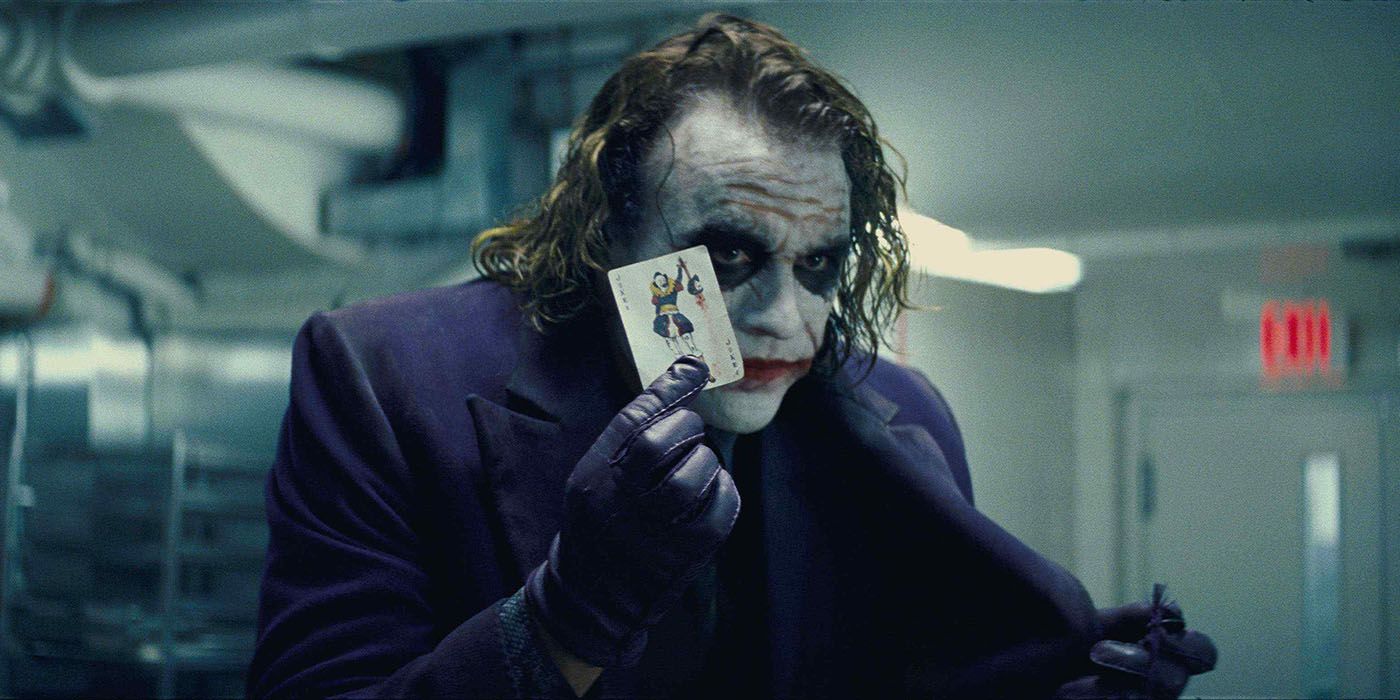 Joker holds up a joker card
