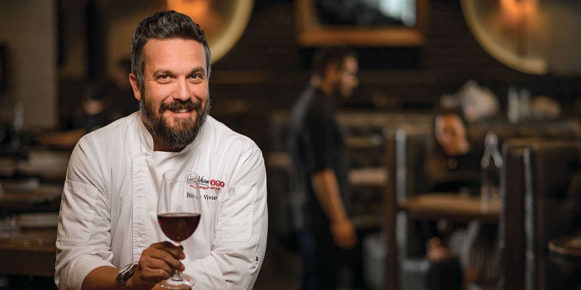 Fabio Viviani smiling while holding a glass of wine