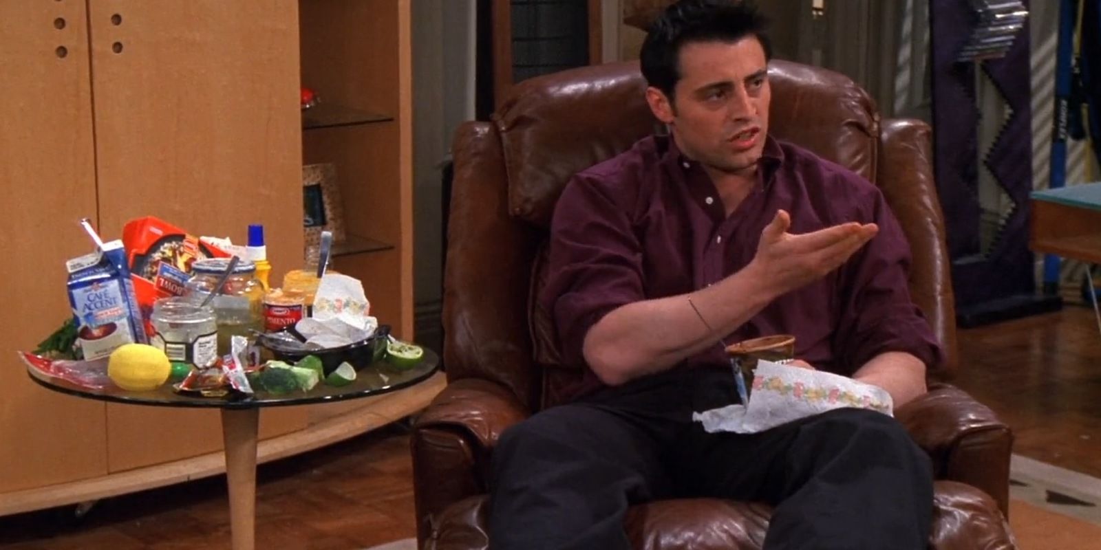 Joey eats ice cream next to empty food packets in Friends