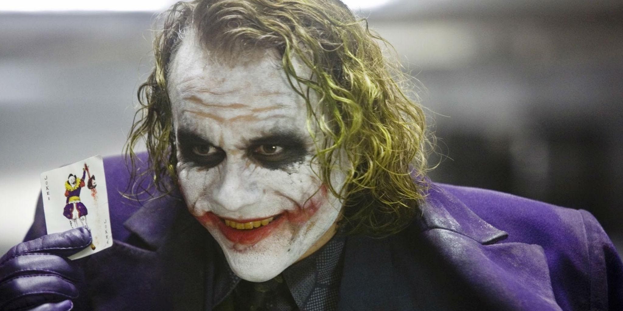 Heath Ledger as the Joker holding a playing card