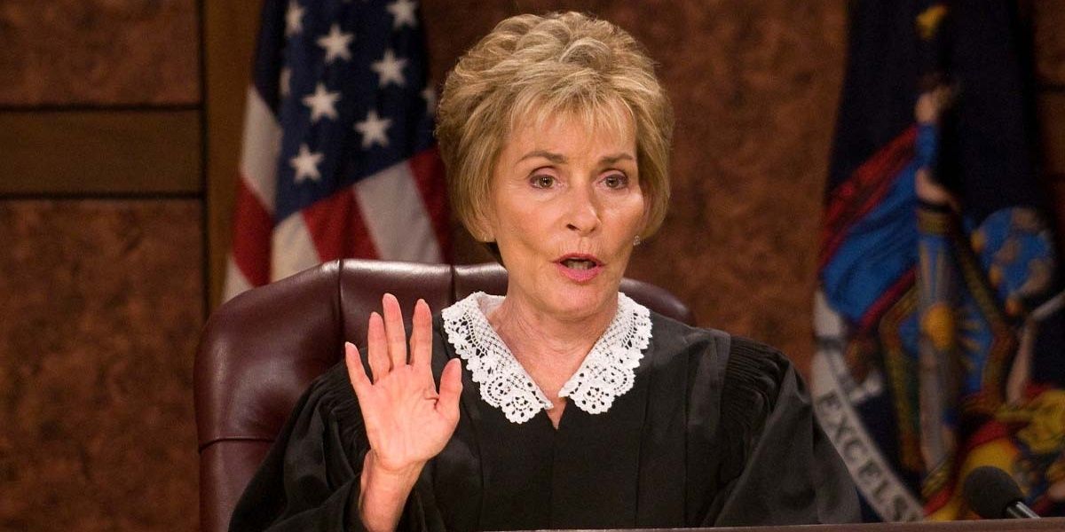 Judge Judy raises her hand in her courtroom