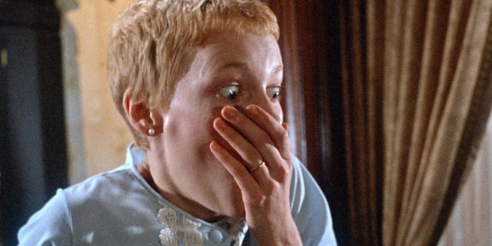 A woman covers her mouth as she screams in Rosemary's Baby.