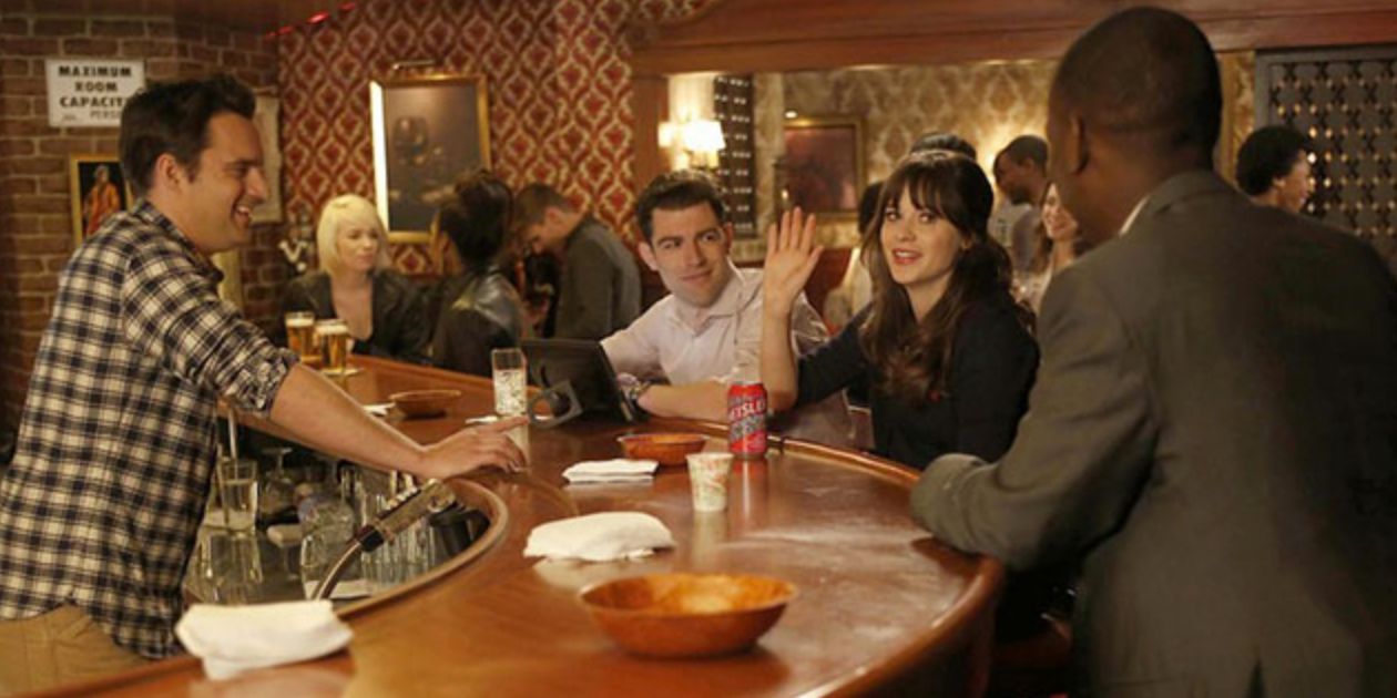 Nick works behind the bar while his friends chat with him at the bar in New Girl