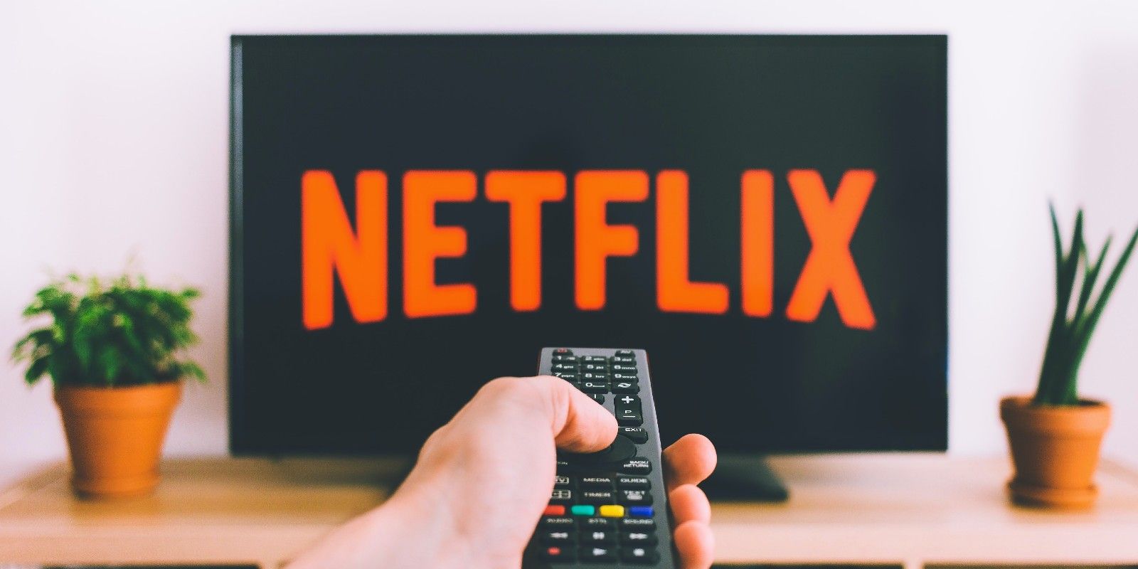 A Hand Pointing a Remote at a TV with the Netflix Logo