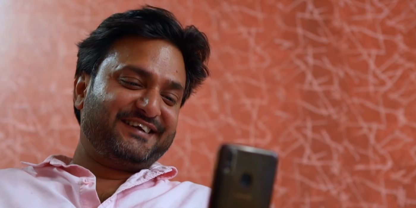 Sumit looking at his phone and smiling In 90 day Fiance
