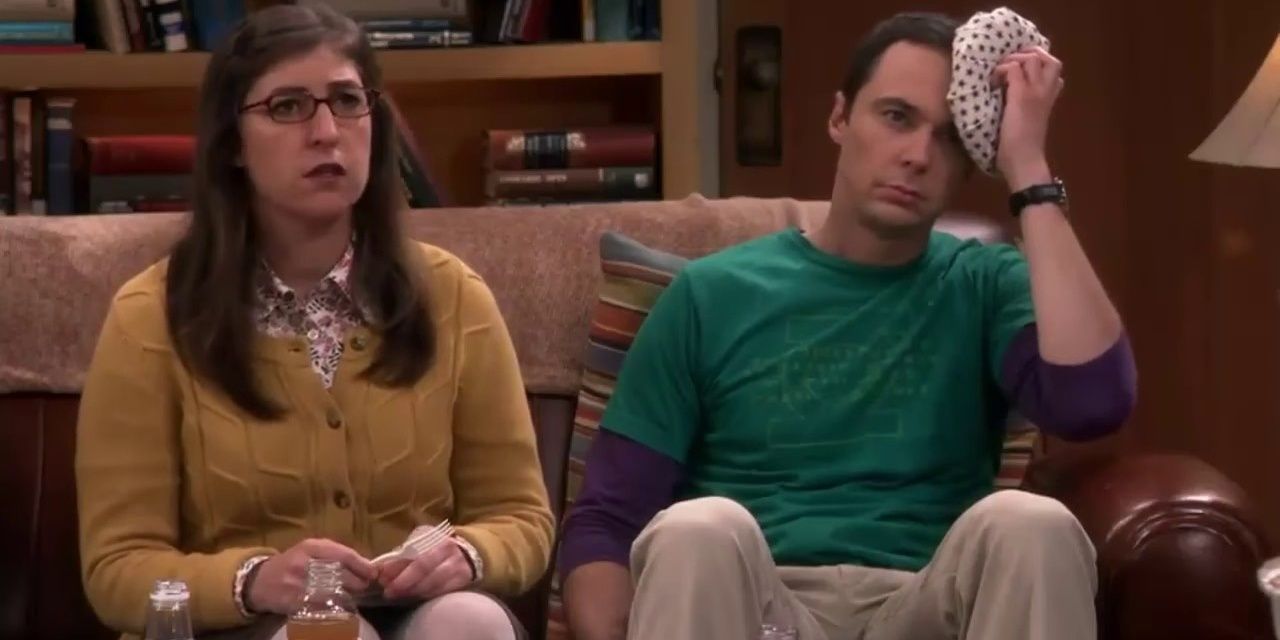 The Big Bang Theory - Sheldon sentado no sofá com Amy segurando gelo na cabeça