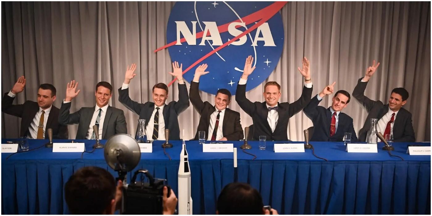 Men in suits waving in front of NASA sign