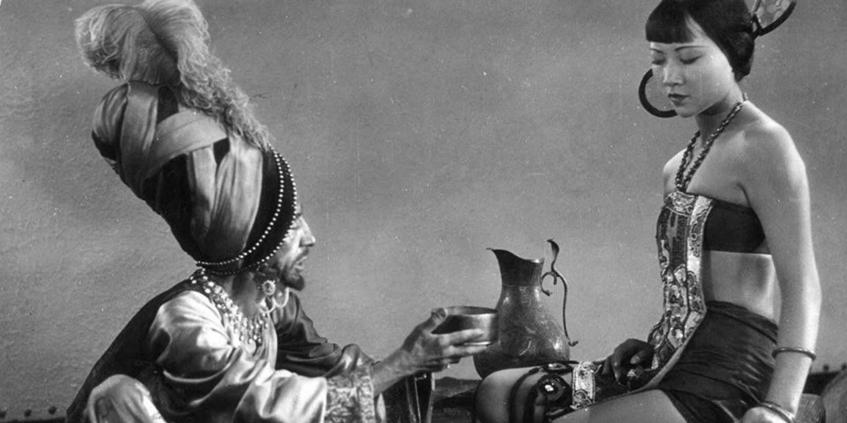 A screensH๏τ of Anna May Wong's Mongol slave being accosted by her Mongol captor from The Thief of Bagdad