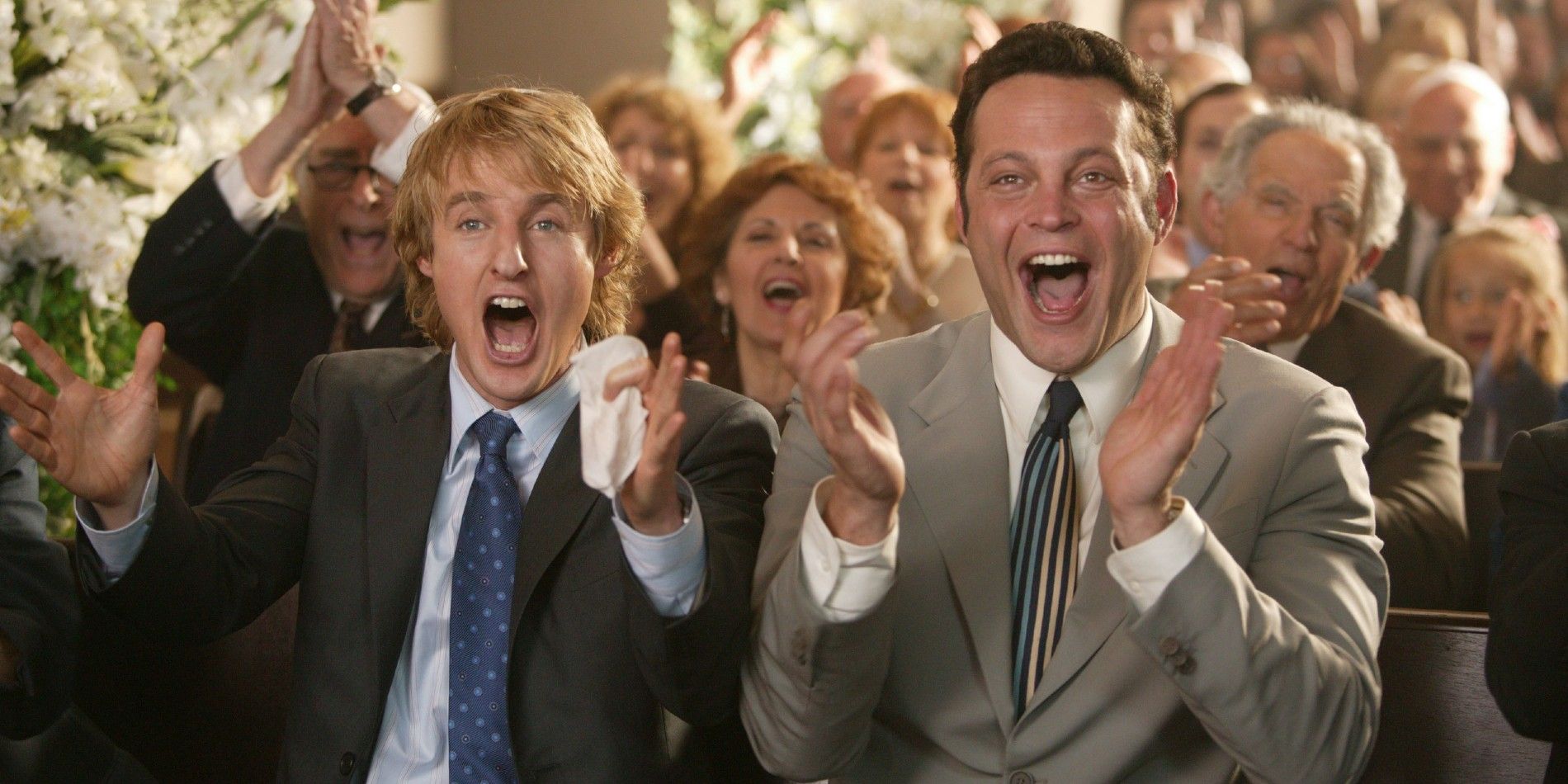 John and Jeremy clap loudly along with the other attendees at a wedding in Wedding Crashers
