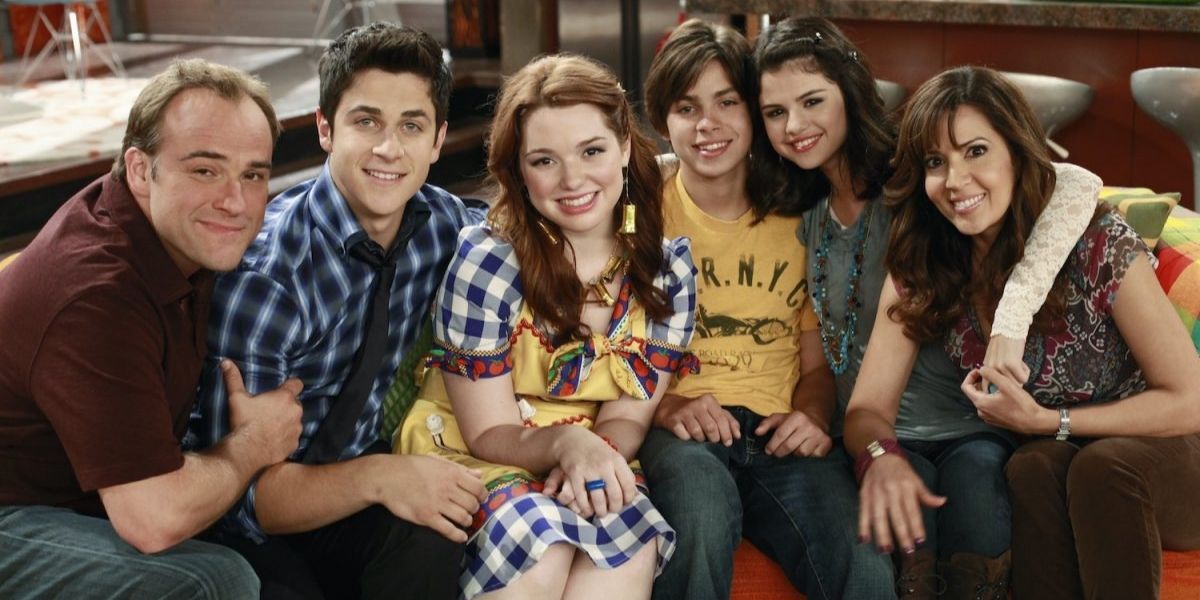 The cast of Wizards Of Waverly Place sit on a sofa and smile
