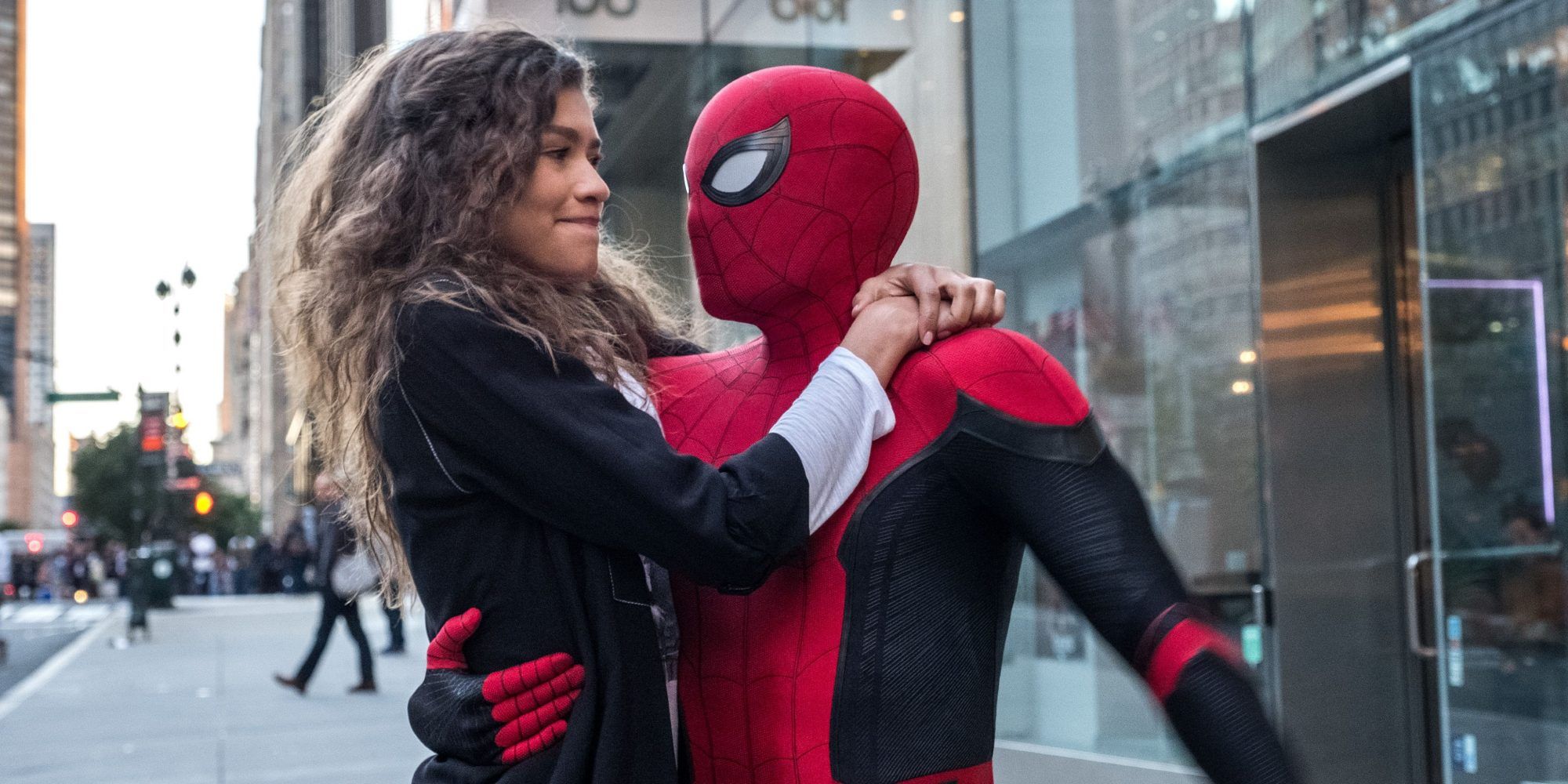 Spider-Man (Tom Holland) holds MJ (Zendaya) on a New York City street.