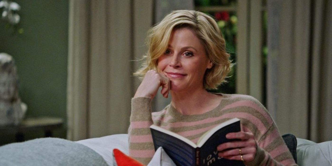 Claire smiling and holding an open book in modern family
