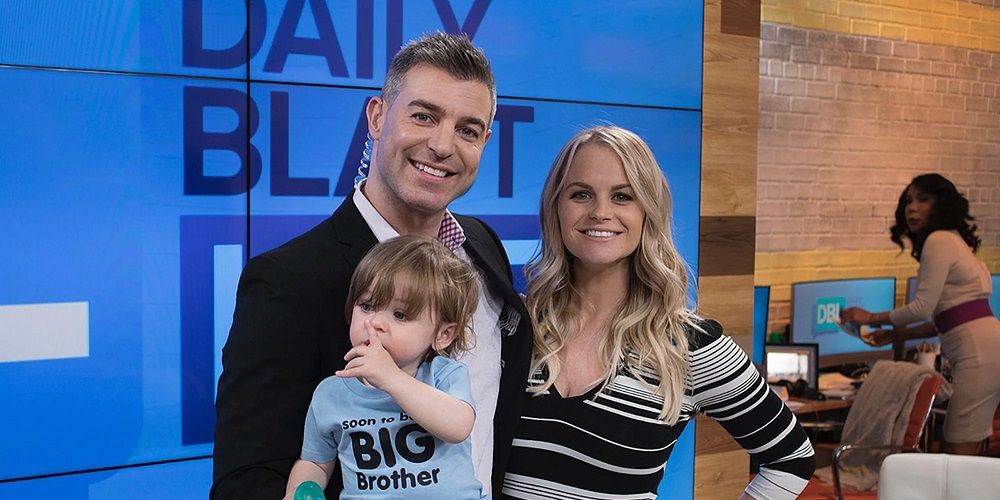 Jordan and Jeff from Big Brother with their child on a TV show set, smiling.