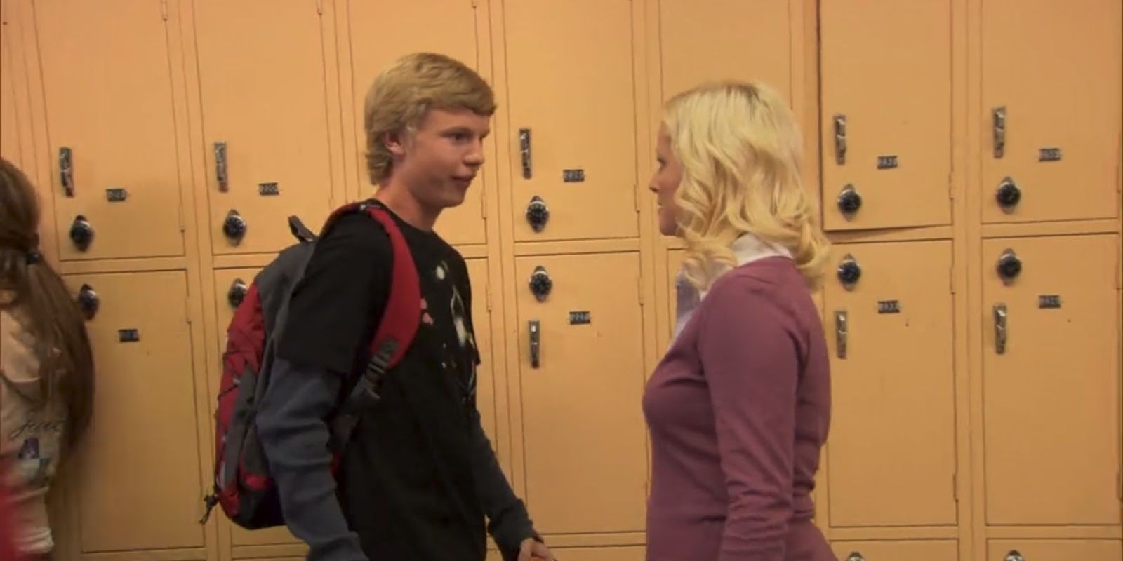Leslie talks to Greg Pikitis in the school hallway.