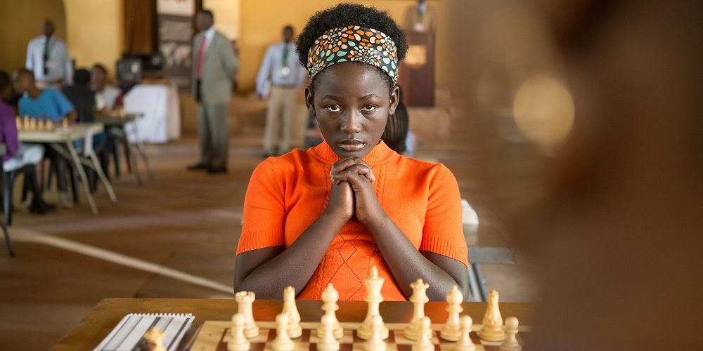 Phiona sitting behind a chess board in Queen of Katwe
