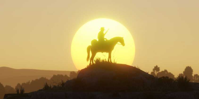 Arthur Morgan sits on a horse in front of a sunset in Red Dead Redemption 2