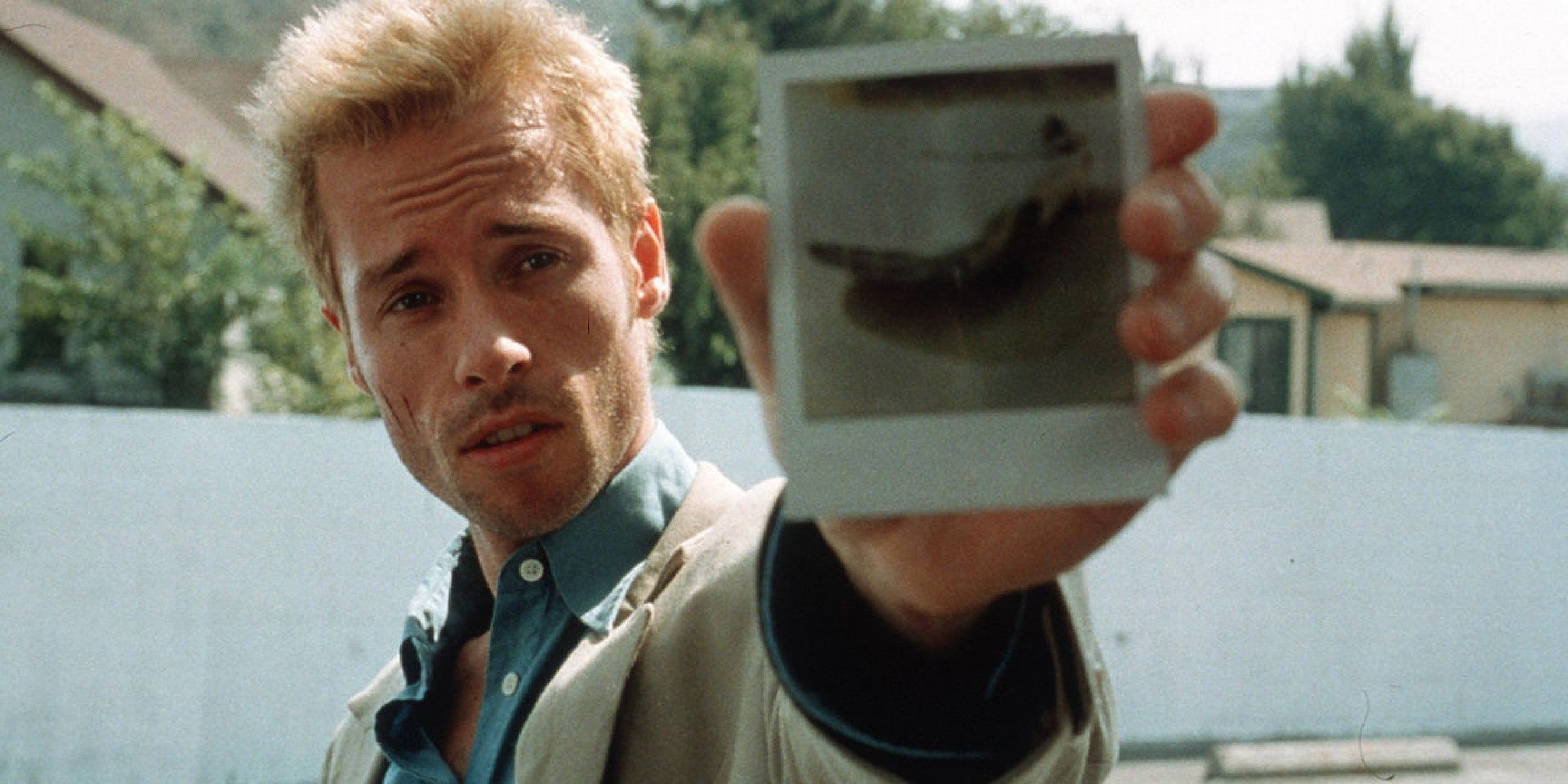 Guy Ritchie holds up a photo of a car in Memento (2001)