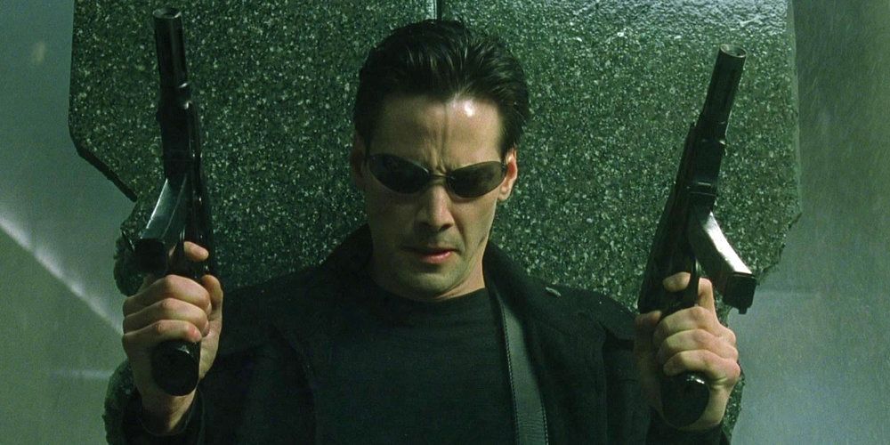 Keanu Reeves holding up two SMGs in The Matrix