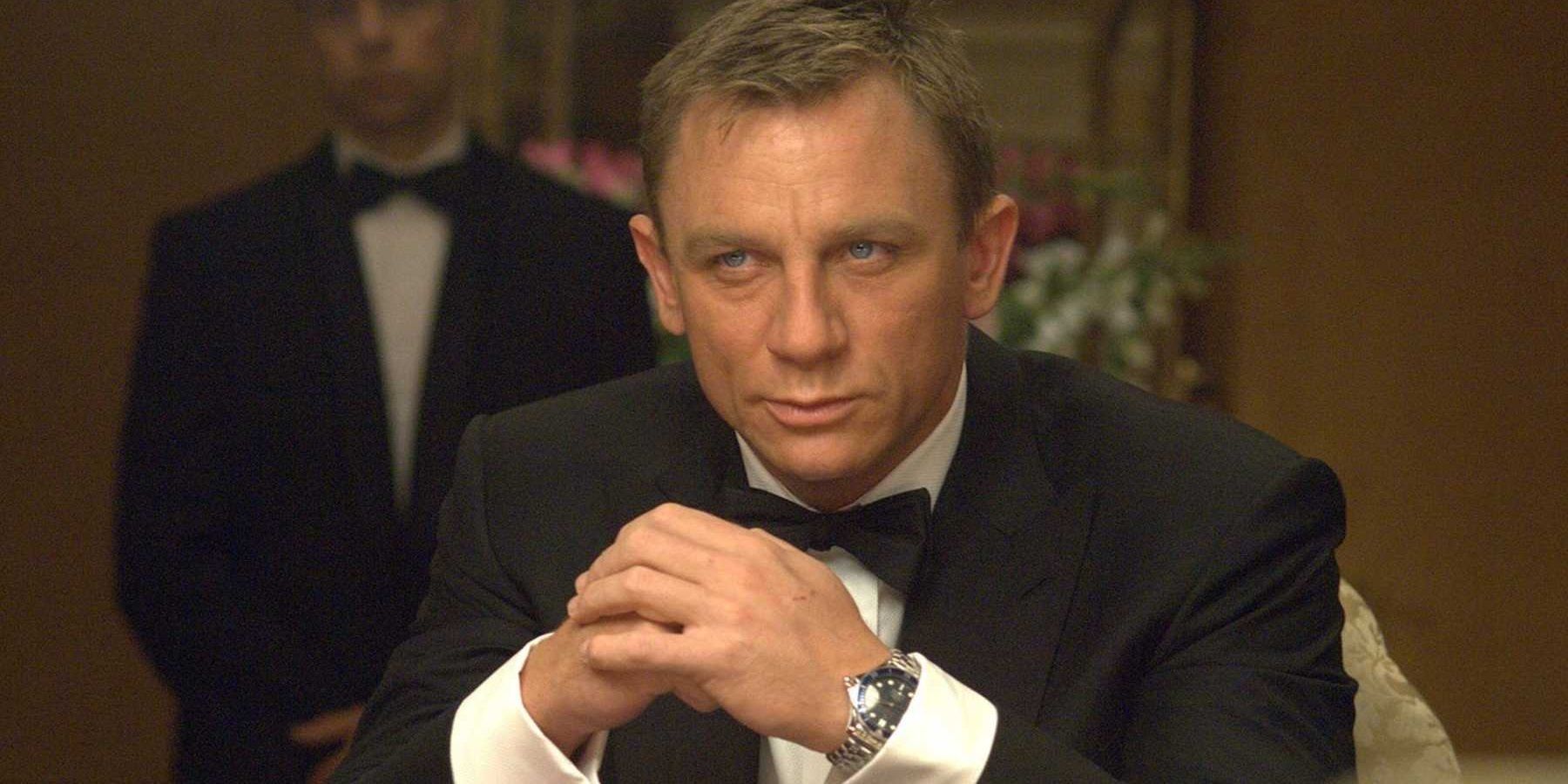 Daniel Craig as James Bond, in tuxedo and sitting at table