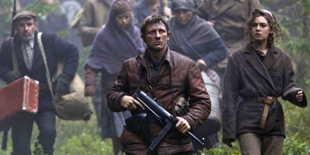 Daniel Craig leads a group of people across a field from Defiance 