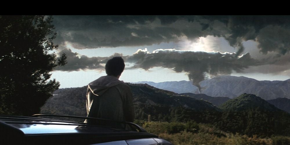 Donnie sits on his car and looks at the sky at the top of a hill in Donnie Darko