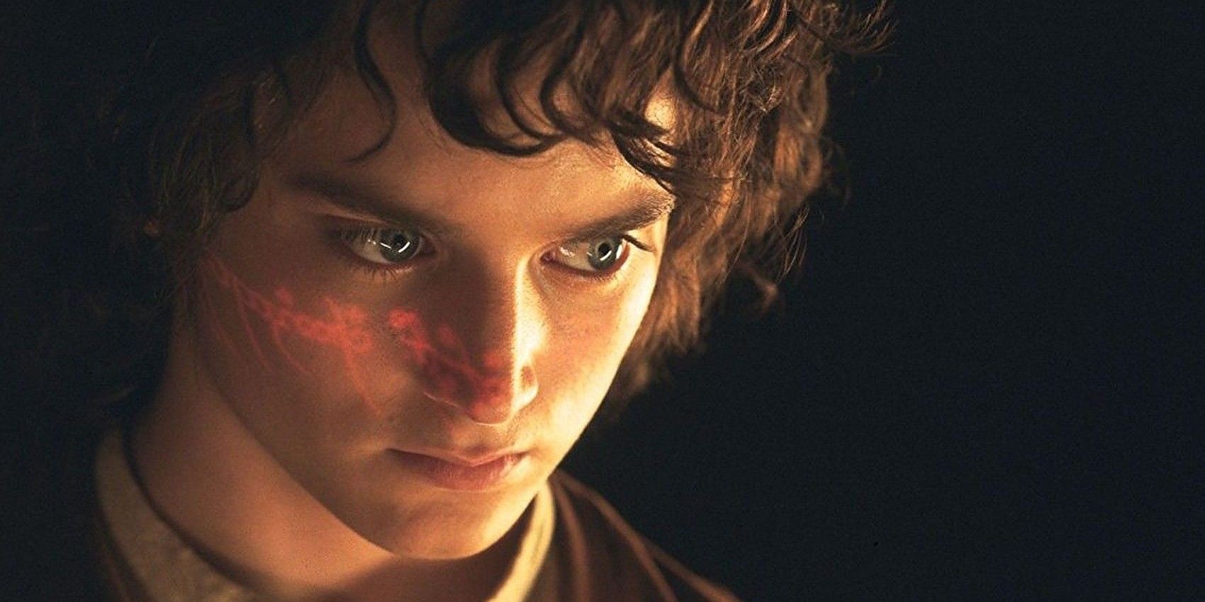 An image of Frodo looking serious as the inscription of the Ring glimmers across his face
