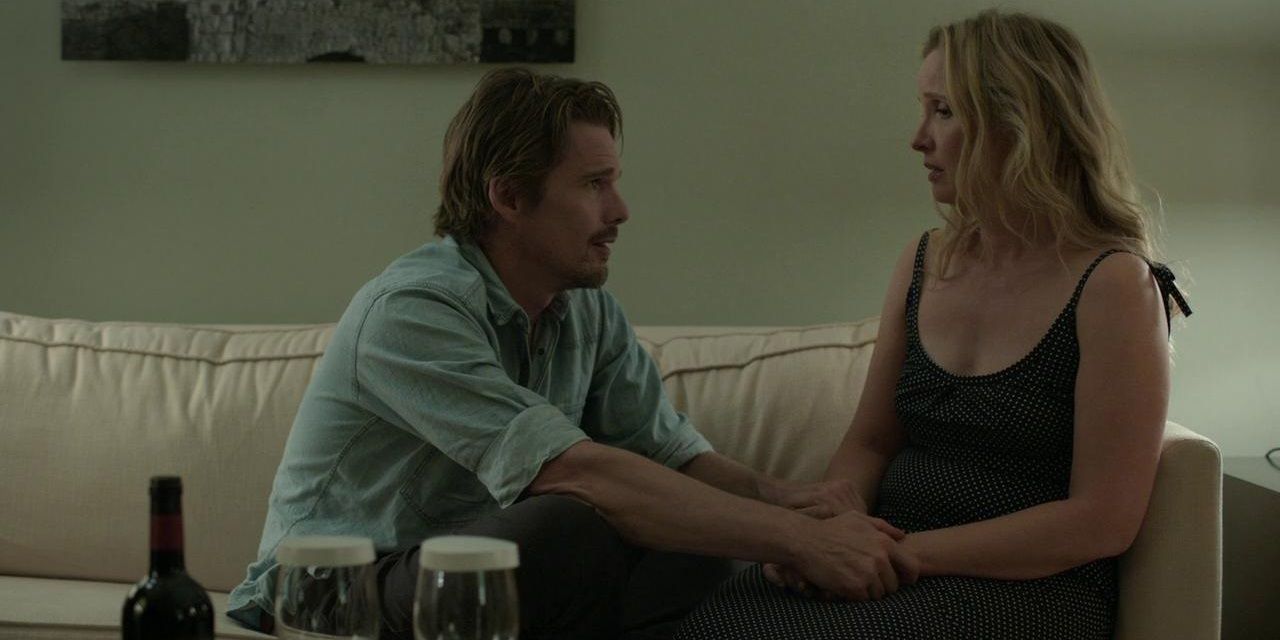 Ethan Hawke and Julie Delpy sitting on a sofa and looking at each other in Before Midnight