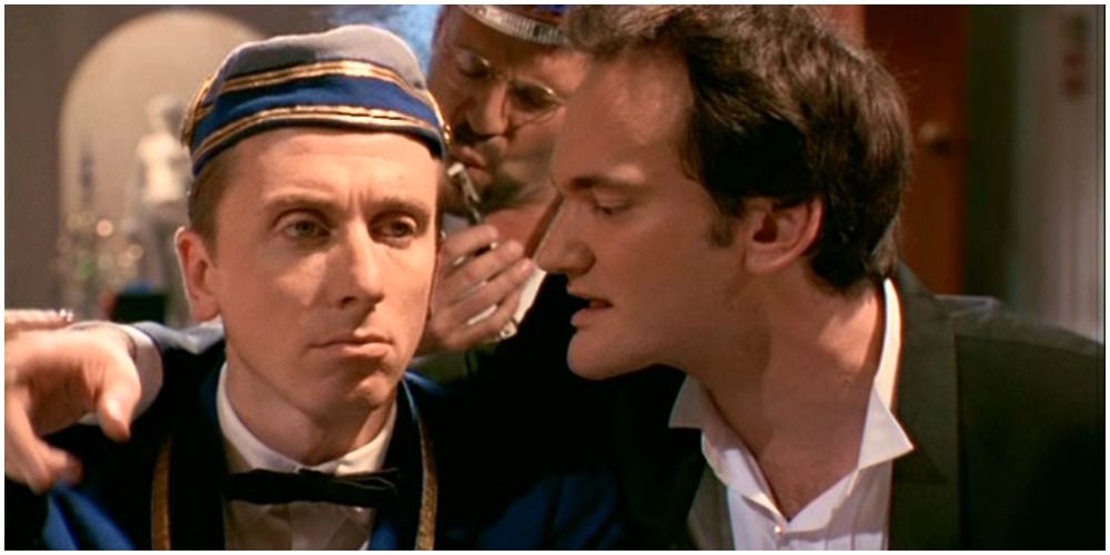 Quentin Tarantino placing his hand on Tim Roth's shoulder and talking to him in a still from Four Rooms