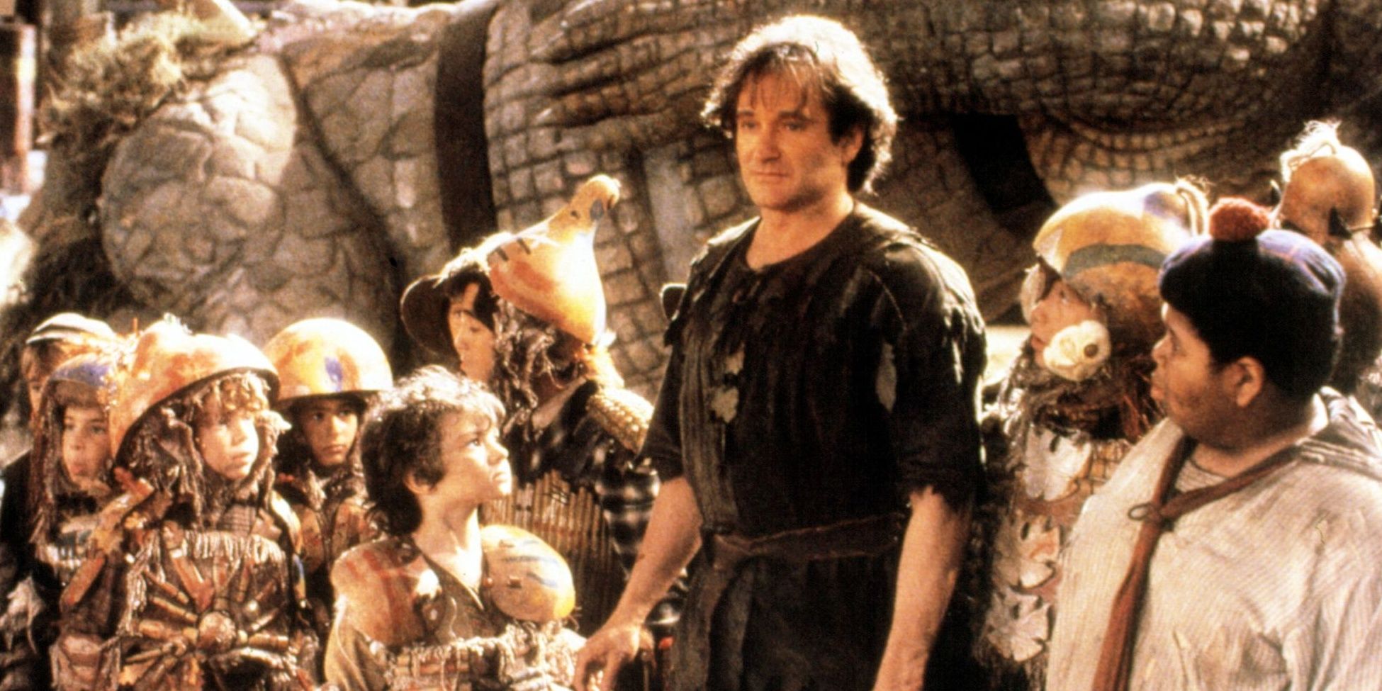 A middle aged Peter Pan stands with the much younger lost boys in Hook