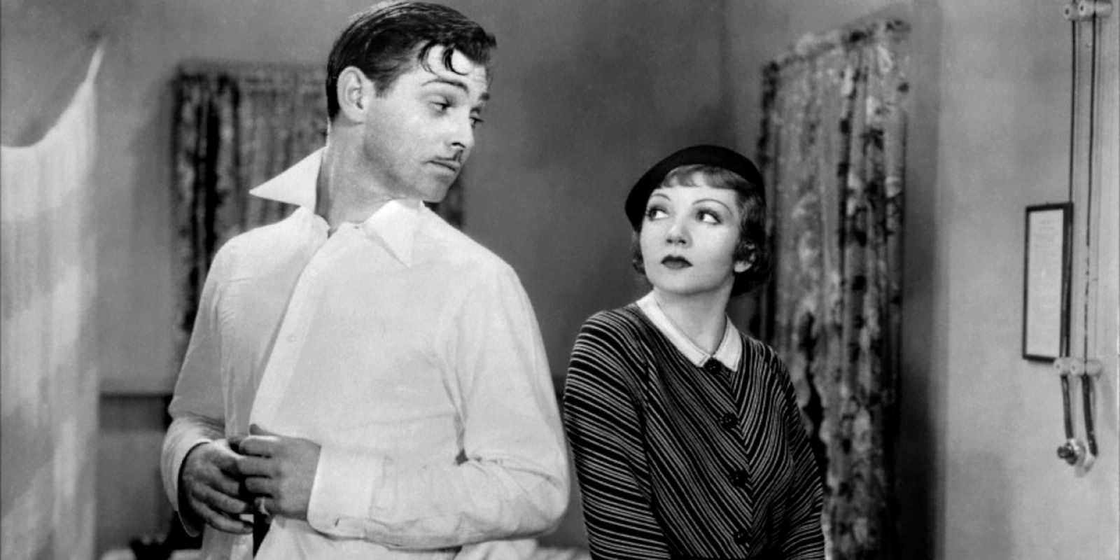 Clark Gabel and Claudette Colbert look back at each other while in a train car in It Happened One Night.