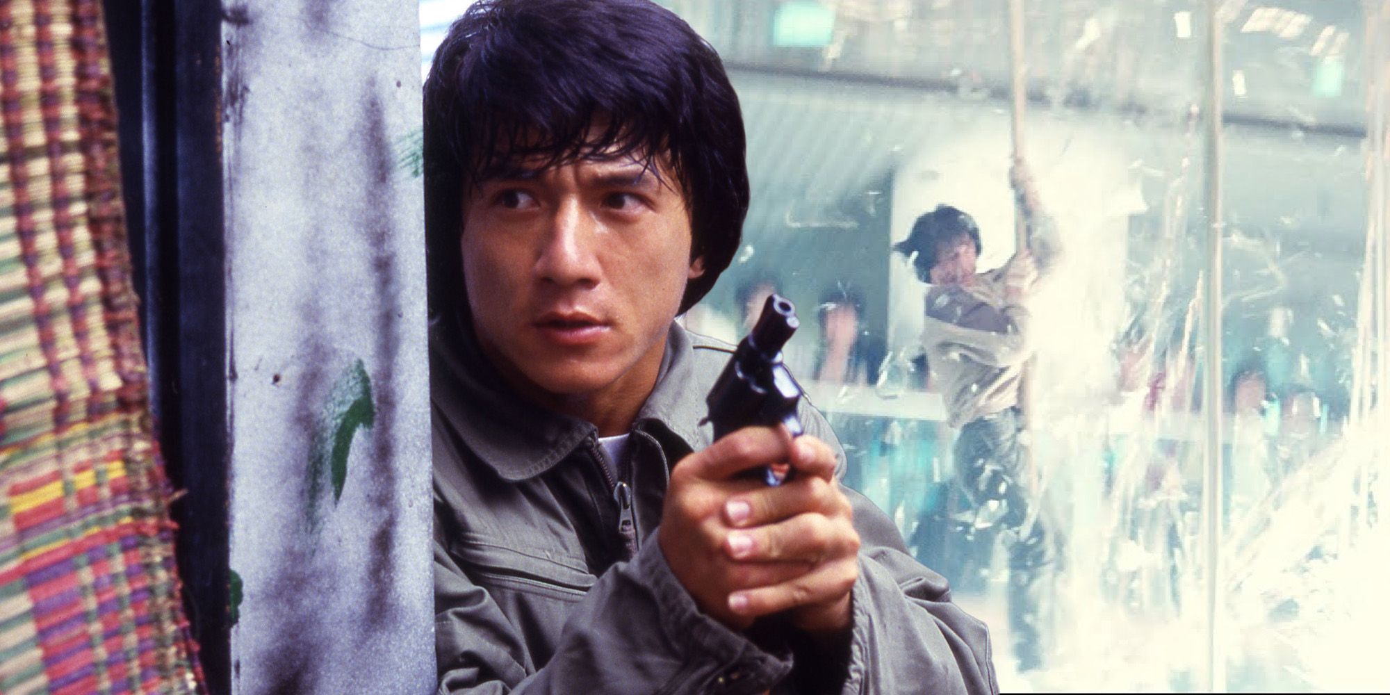 Chan Ka-Kui holding a gun and hiding behind a wall
