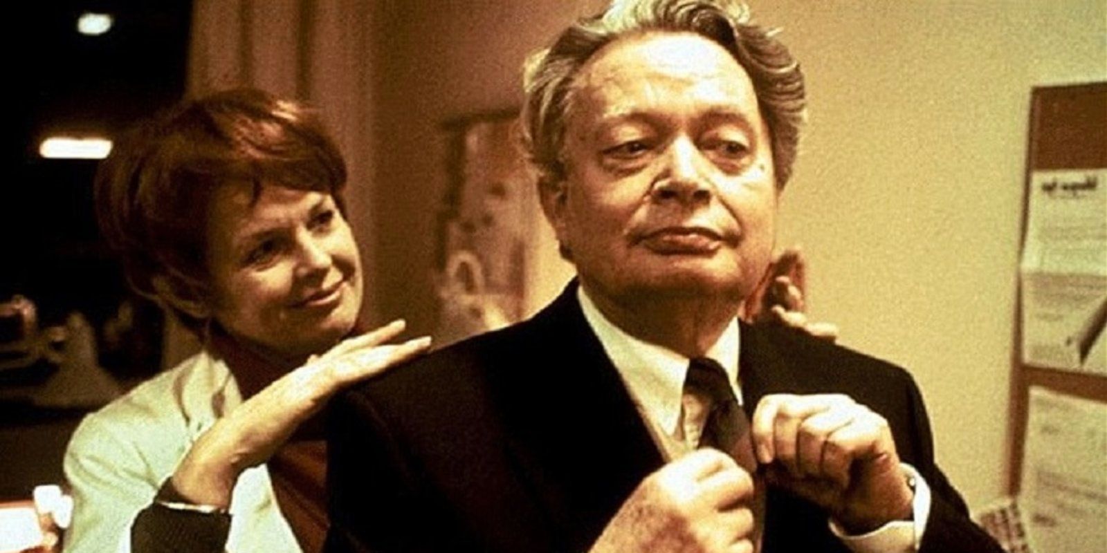 A scene from Lars von Trier's TV show The Kingdom featuring a man knotting a tie while a woman gleefully looks at him