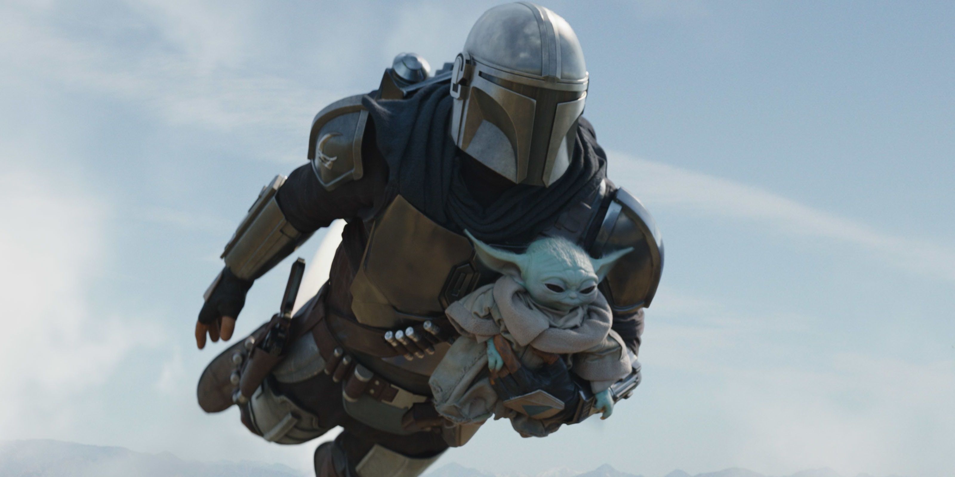 Mando flying and holding Grogu in The Mandalorian