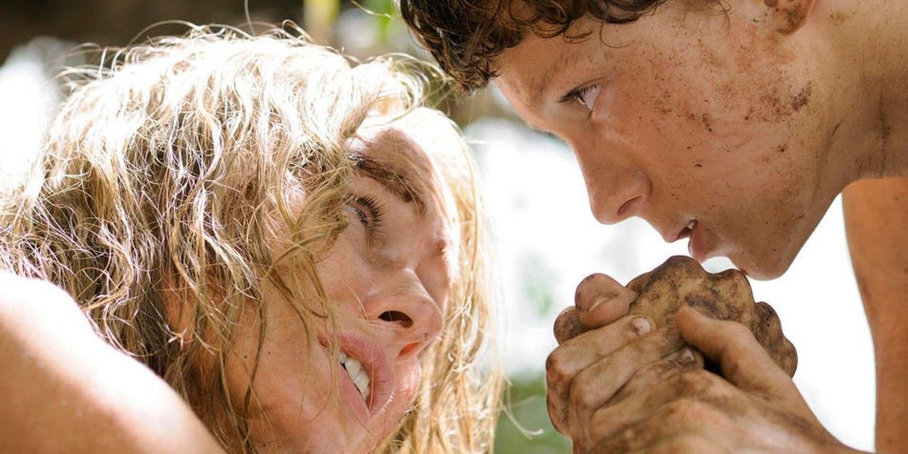 Naomi Watts and Tom Holland holding hands and looking at each other in The Impossible