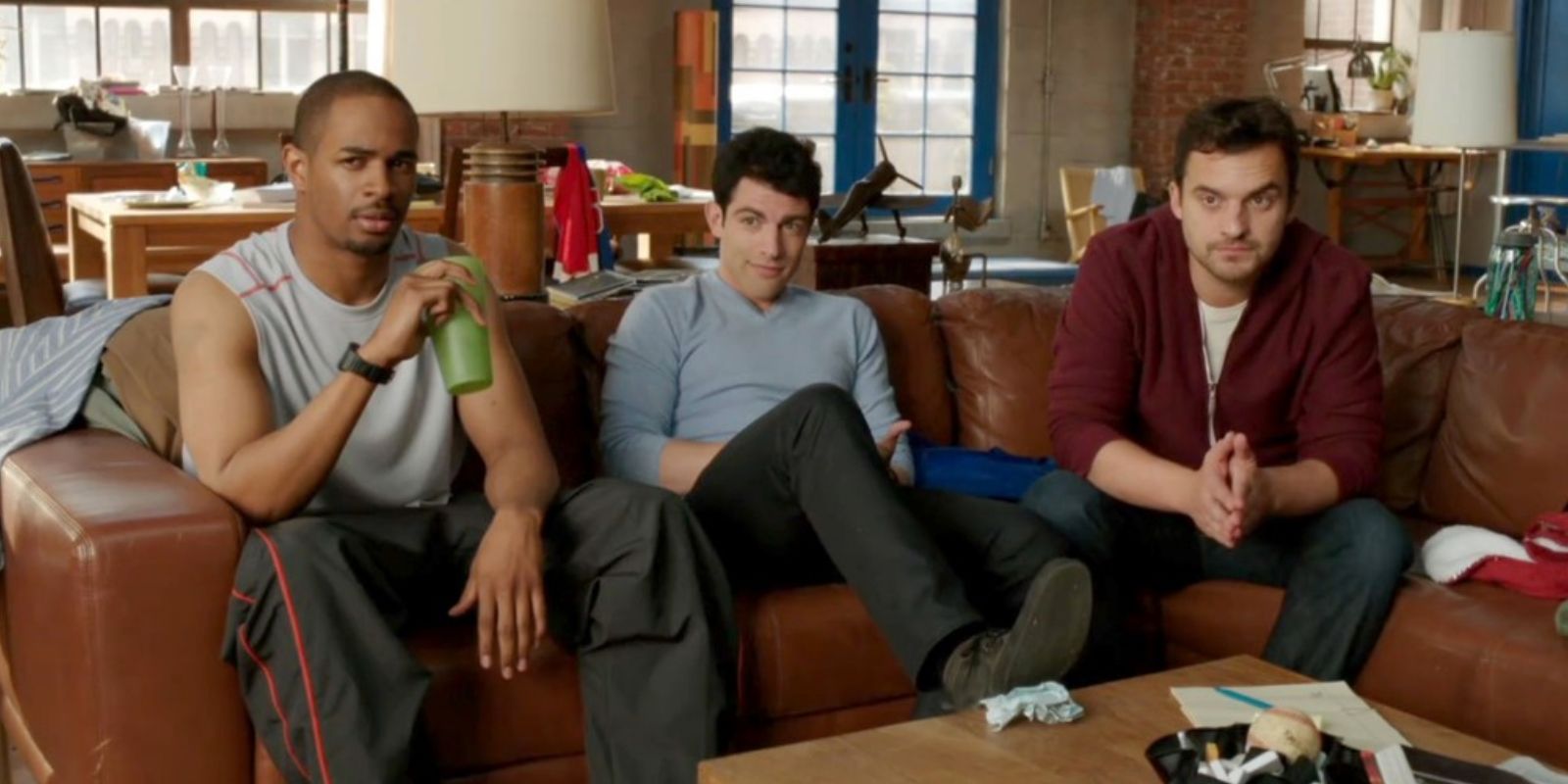 Coach, Schmidt, and Nick sit on the couch in the loft as they question Jess in the New Girl pilot episode