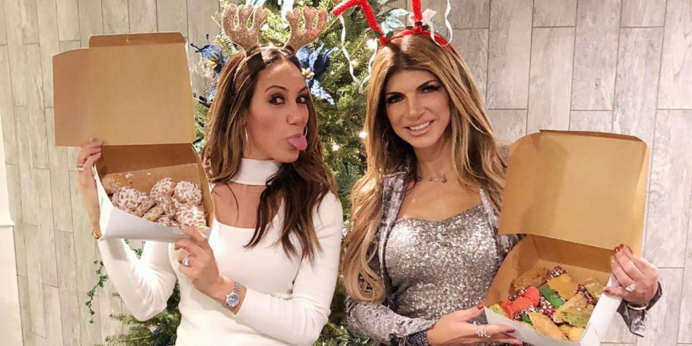 Melissa sticking her tongue out and Teresa smiling while holding up sprinkle cookies in boxes on RHONJ