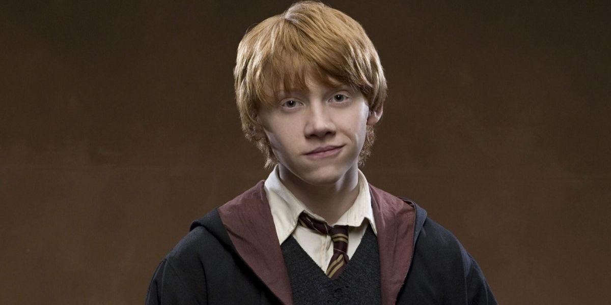 Ron Weasley in his school uniform against a brown background.