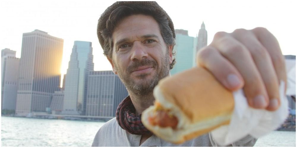 Man With Hotdog Standing In Front Of City Skyline