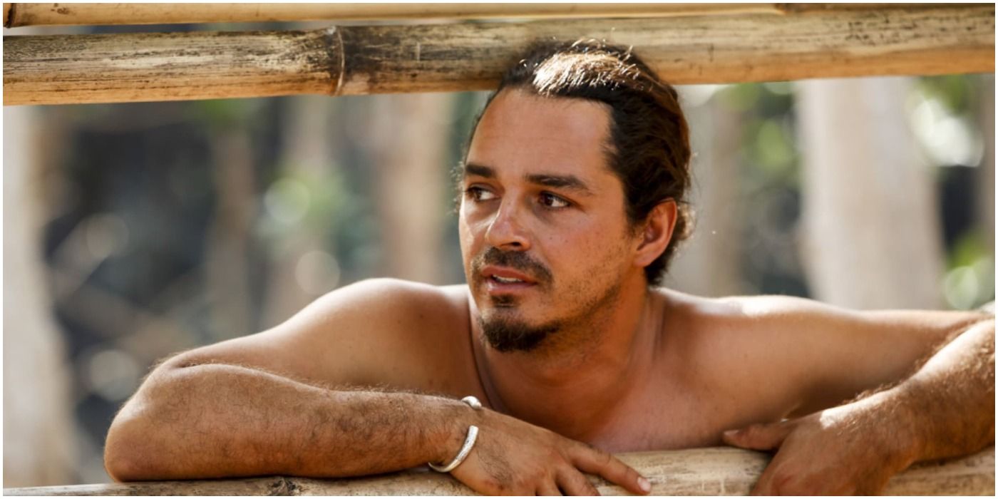 Ozzy Lusth from Survivor, arms and head between two pieces of wood.