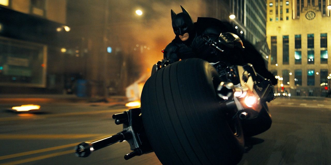 Batman rides on his motocycle in the streets of Gotham in The Dark Knight.