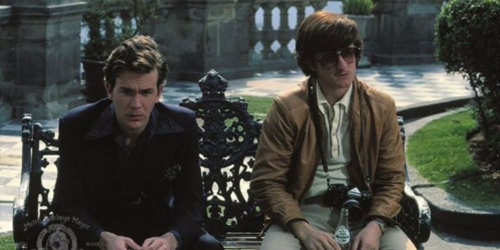 Timothy Hutton and Sean Penn sit emotionless on a bench together. 