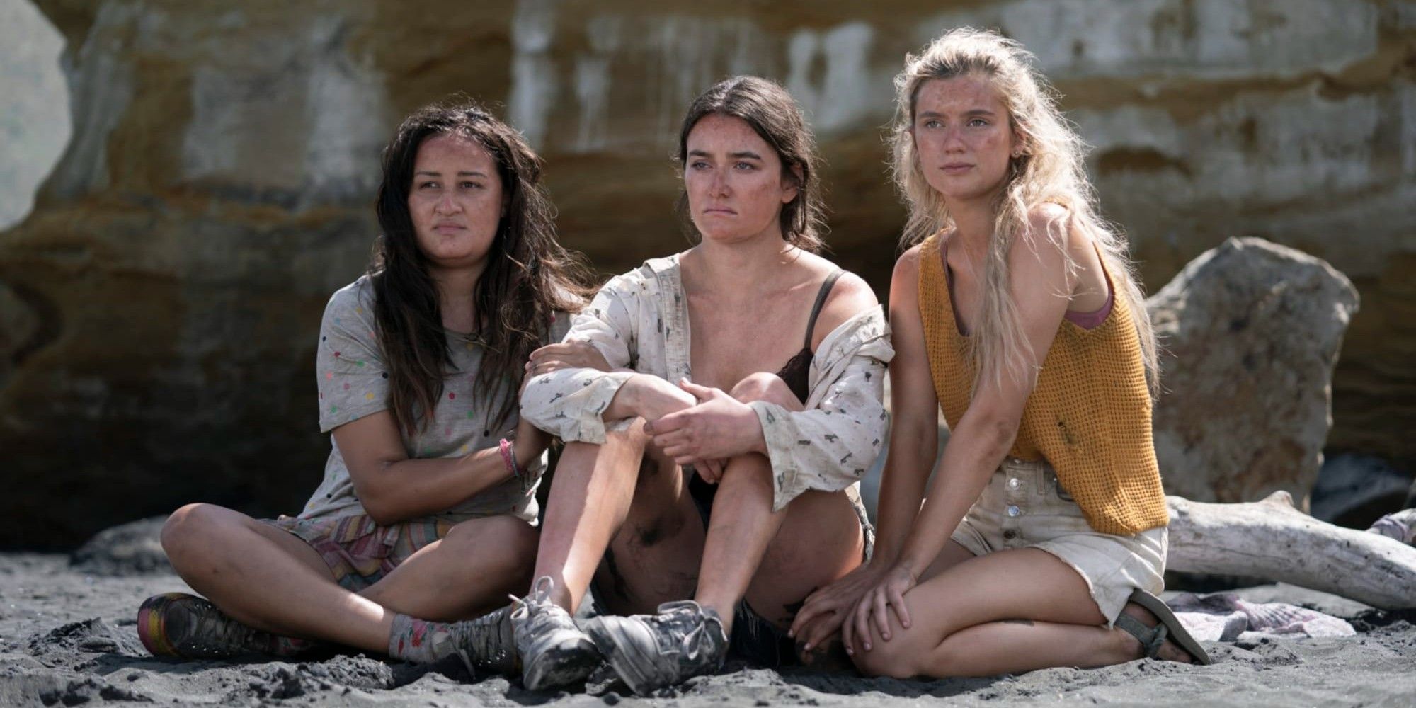 Three girls from The Wilds sitting on the island, looking dirty and upset.