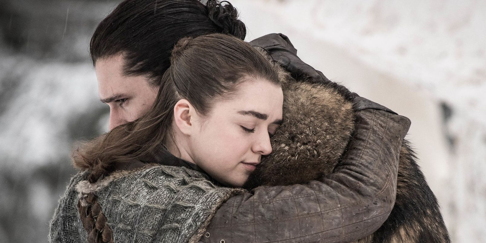 Arya abraçando Jon em um campo nevado em Game of Thrones.