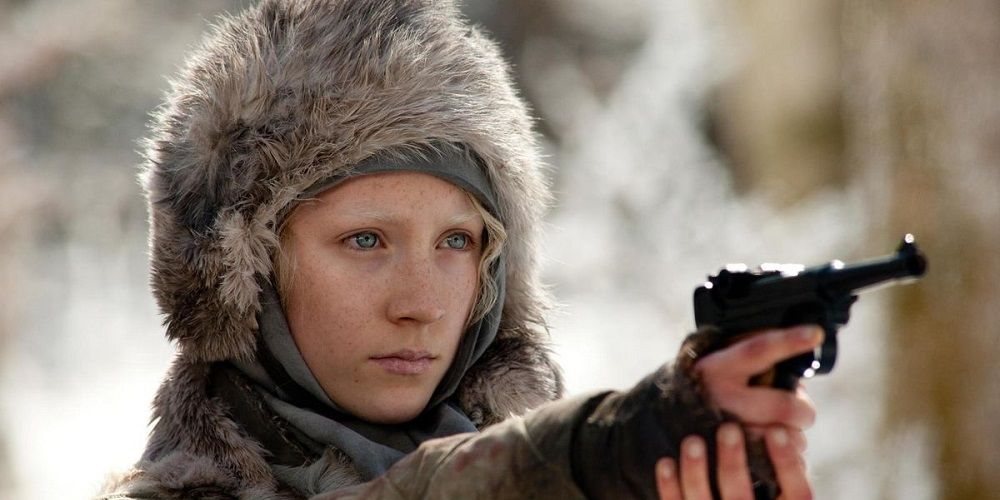 Saoirse Ronan wears a furred hood and points a gun in Hanna.