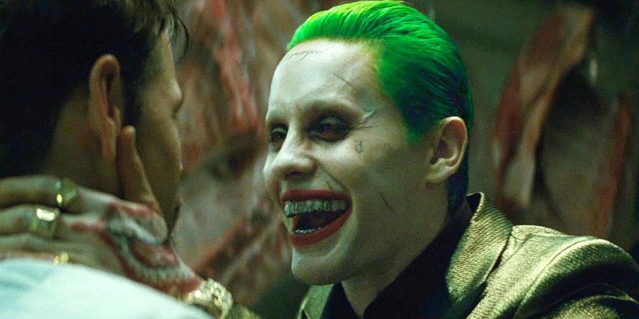 Joker grins as he grabs somebody's neck in Suicide Squad.